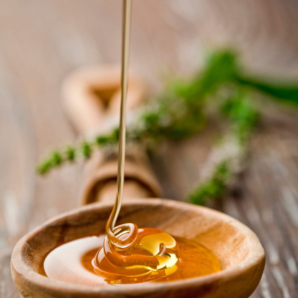 wild honey wooden spoon with wild honey falling into it